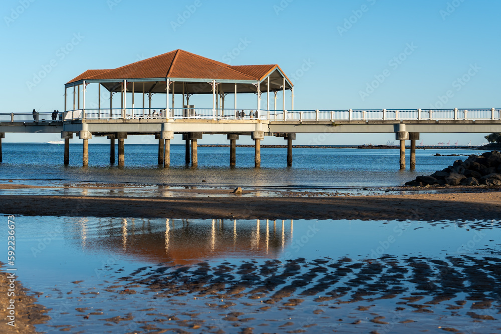 Redcliffe Jetty rotunda reflected in pool of water at low tide.  Port of Brisbane on the horizon. Redcliffe, Queensland, Australia 