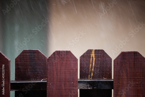 Raindrops falling over the wooden fence before the blurred background