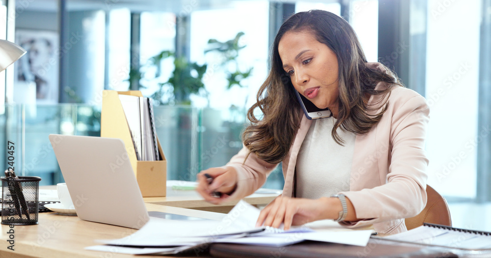 Female advertising agent looking busy while talking on a phone call and searching through documents on a messy table in an office. Female marketing professional trying to find an important form Female advertising agent looking busy while talking on a phone call and searching through documents on a messy table in an office. Female marketing professional trying to find an important form