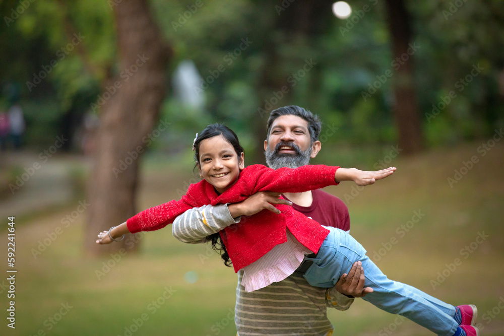 Fototapeta premium Indian man playing with his daughter at park