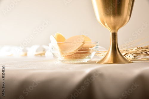 Detail of cup and hosts on white tablecloth front view