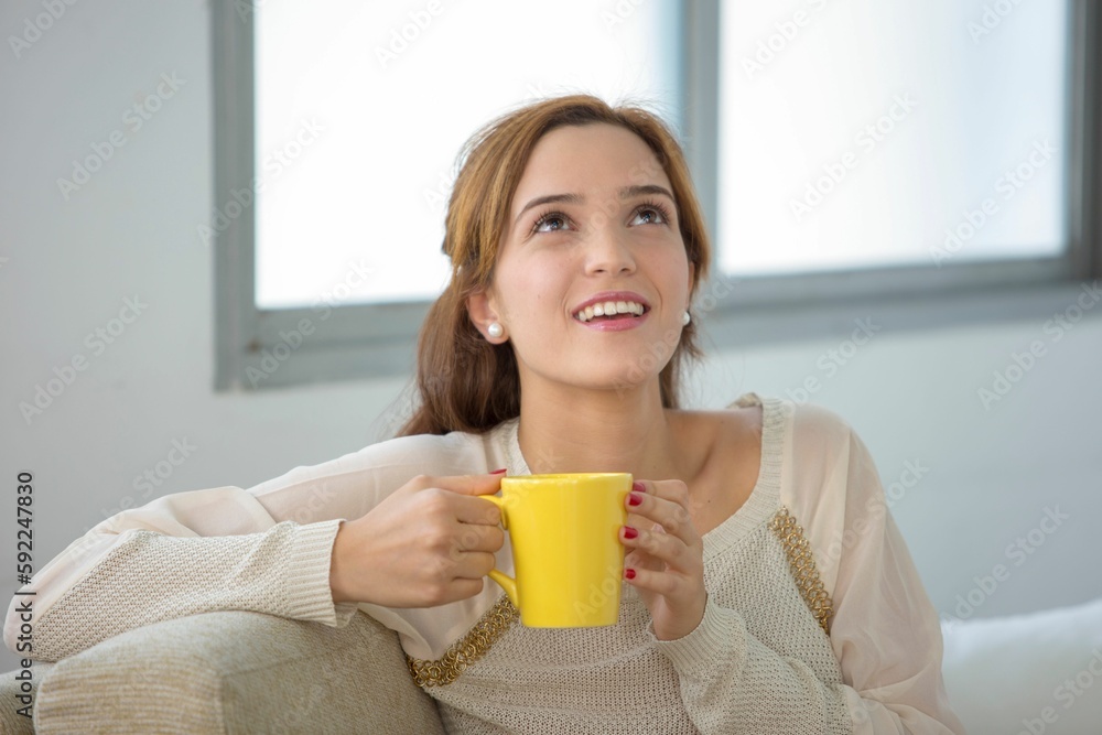 Woman holding yellow cup and looking up with smile in white background Woman holding yellow cup and looking up with smile in white background