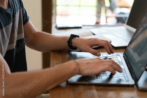 Person sitting at a laptop and typing something © Enric Nogueras Monserrat/Wirestock Creators