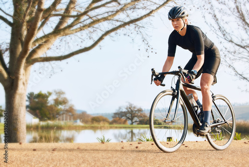 Fototapeta Naklejka Na Ścianę i Meble -  Fitness, bicycle and woman cycling in a forest for sports, exercise and morning cardio in nature. Training, bike and female enjoying workout in a park, freedom and energy, performance and endurance