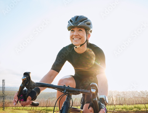 Cycling, fitness and happy with woman in park for training, workout and cardio health. Exercise, travel and freedom with female cyclist riding on bike in nature for adventure, journey and transport photo