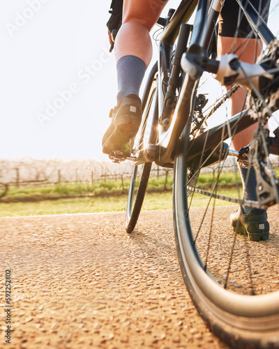 Bicycle closeup, countryside ride and person on a bike with speed for sports race on a gravel road. Fitness, exercise and athlete legs doing sport training in nature on a trail for cardio and workout