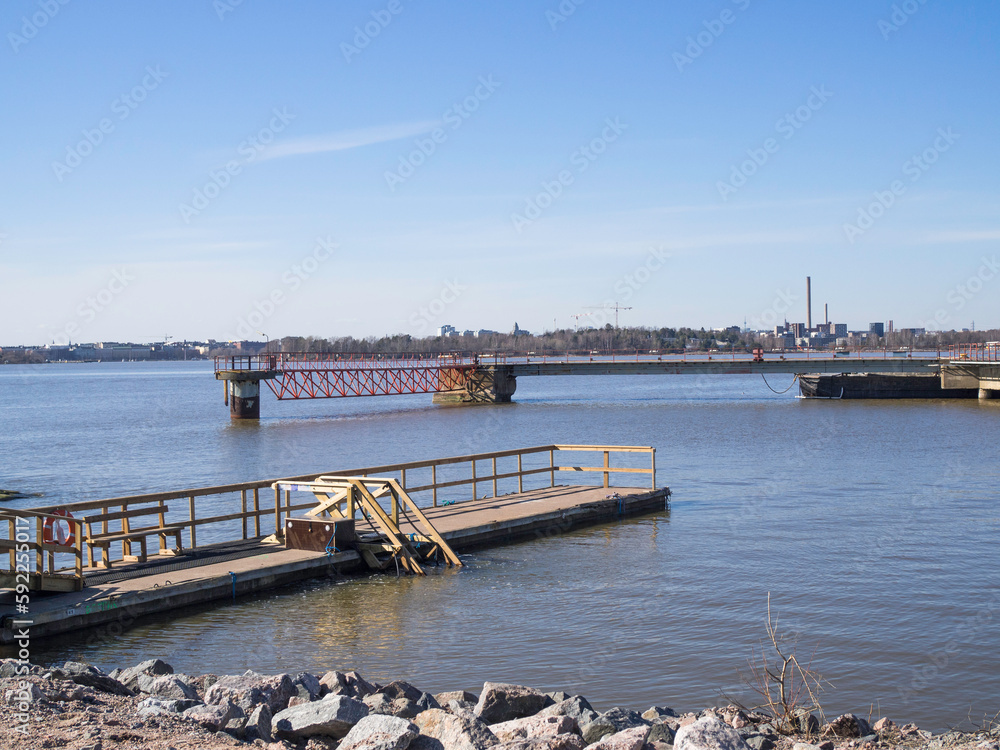 Piers at Kruunuvuori shore in Helsinki, a pier for winter swimmers on the left, Helsinki down town on the horizon, sunny day in April