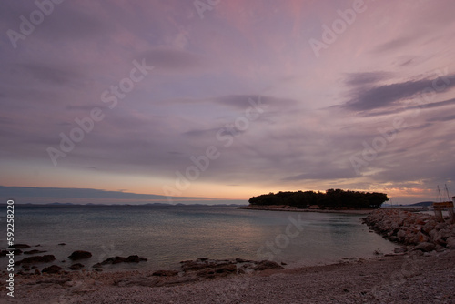 pastel colored sunset with an island and the silhouette of the kornati islands in the background