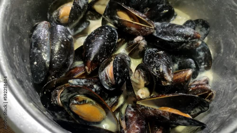 The chef cooks mussels in a shell in blue cheese sauce The chef cooks mussels in a shell in blue cheese sauce