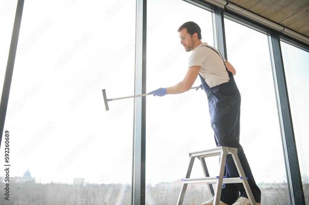 An employee of a professional cleaning service washes the glass of the windows of the building. Showcase cleaning for shops and businesses.