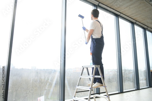 An employee of a professional cleaning service washes the glass of the windows of the building. Showcase cleaning for shops and businesses.