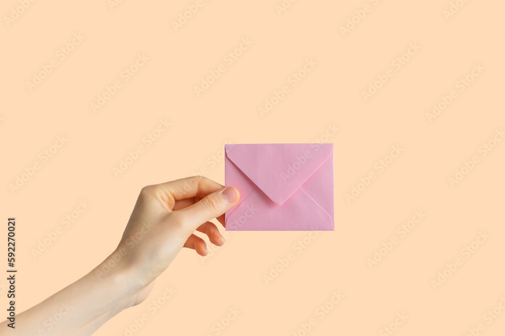 hand holds an envelope on a pastel background. isolated background with hand and letter. message and message concept.