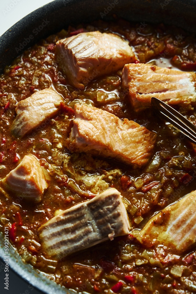 Frying pan with Indian salmon curry dish. Fried salmon fillets, stewed