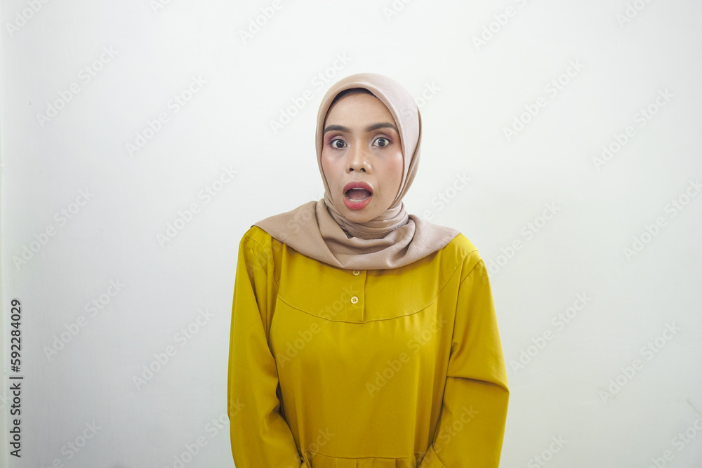 Fototapeta premium A portrait of a shocked Asian woman wearing a mustard casual dress, isolated by a white background
