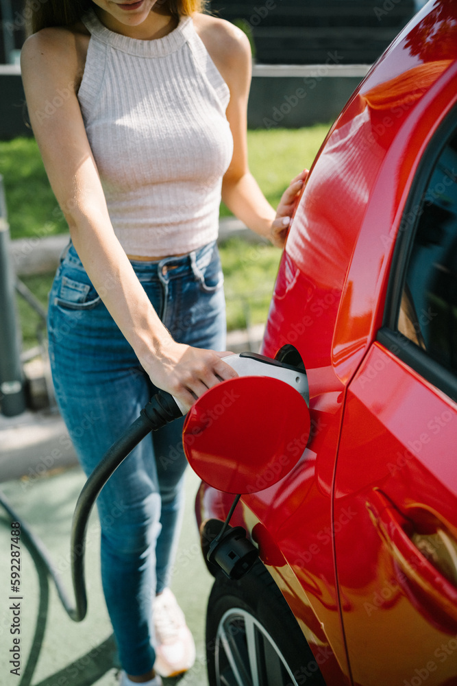 Woman charging electric car in station Woman charging electric car in station