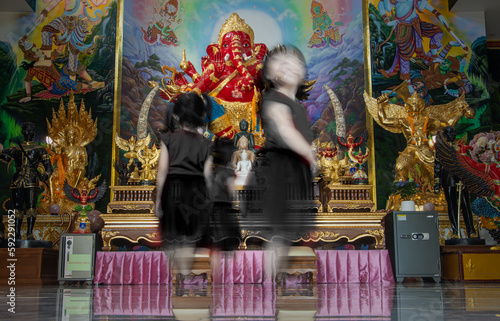 Blurred outlines of little girls in front of an altar in a buddhist temple, Thailand