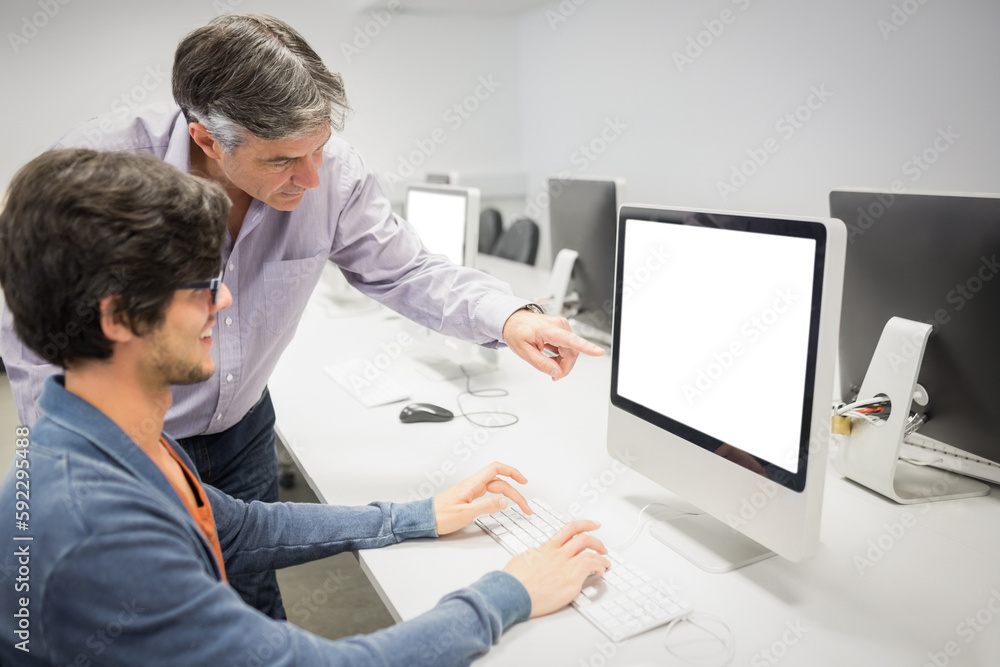 Businessman pointing at computer while explaining colleague