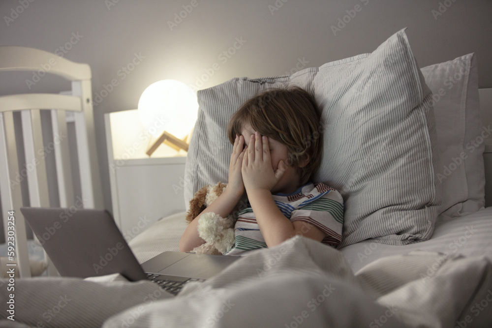 The child watches horror on the laptop before a sleep.Baby see some scary videos before a sleep on the the laptop. Toddler watch a movie before a sleep and have panic. The child watches horror on the laptop before a sleep.Baby see some scary videos before a sleep on the the laptop. Toddler watch a movie before a sleep and have panic.