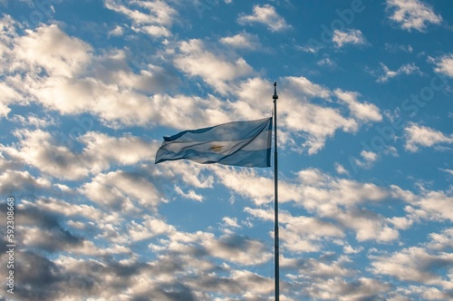 Argentinian National Flag waving against a backdrop of clouds and sky reminiscent of its colors © Patricio Murphy/Wirestock Creators