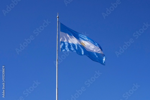 Daytime view of Argentina's national flag waving against a blue sky