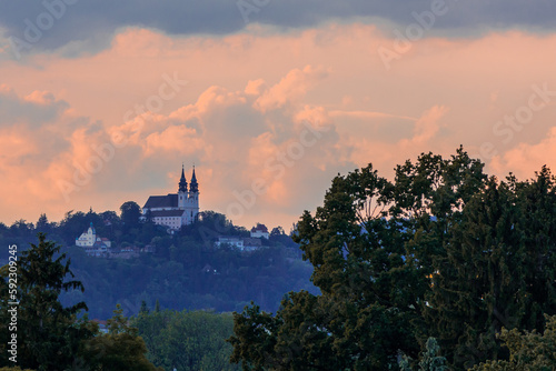 Postlingberg pilgrimage church on a high hill in front of a dramatic pink sky, Austria photo