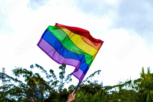 Waving LGBT flag in background of blue bright sky