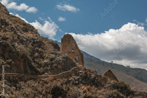 Stone wall with square arched doorway at the archaeological site of Ollantaytambo with a blue sky with white clouds, in Peru.