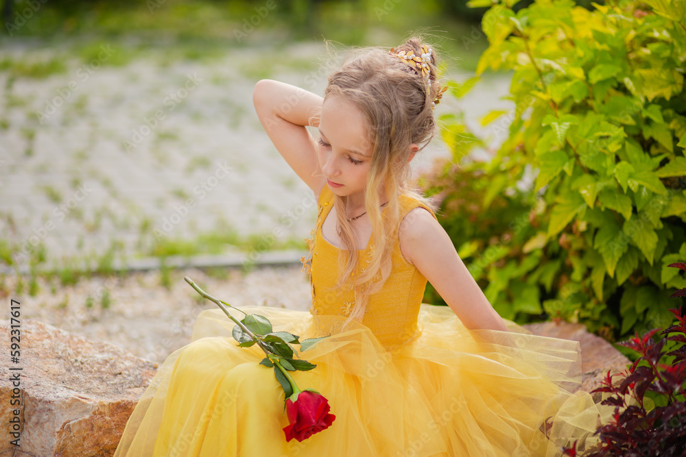 Little girl in a yellow fairy dress with a rose in her hands. The