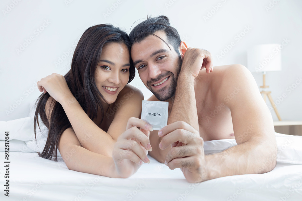 Couple Lying on Bed Holding Condom For Safety Sex Couple Lying on Bed Holding Condom For Safety Sex