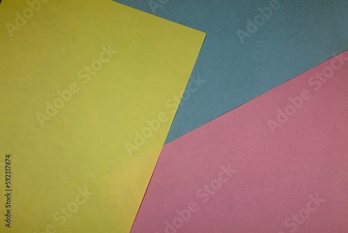 Top view of yellow, blue, and pink colored papers on the table