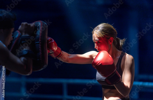 Female kickboxing training with male trainer gives self-defense classes to female fighter at GYM. Asian beautiful young woman exercise with trainer at boxing gloves, uppercut short, boxing, training