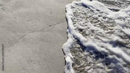 The sea wave washes away the traces of women's feet left on the sand. High quality 4k footage