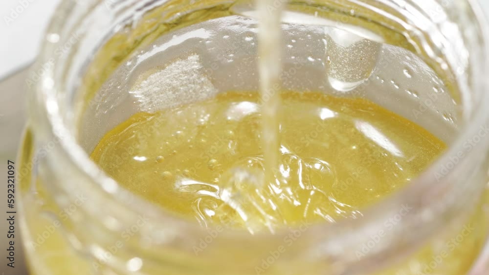 natural bee honey is poured into a jar natural bee honey is poured into a jar