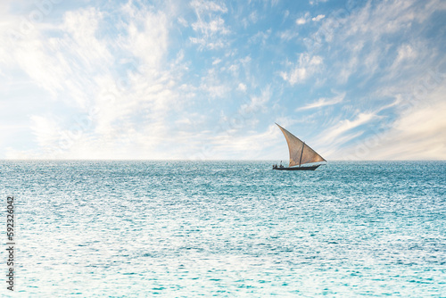 Traditional African dhow sailing in the calm waters of the Indian Ocean, Zanzibar, Tanzania photo