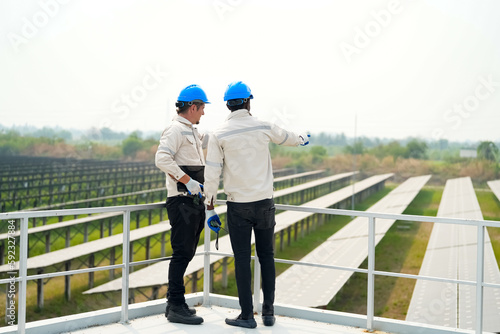 Electrician engineer with white helmet working at a photovoltaic farm, checking and maintenance equipment with instruments at industry solar power.