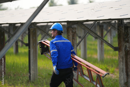 Electrician engineer with white helmet working at a photovoltaic farm, checking and maintenance equipment with instruments at industry solar power.