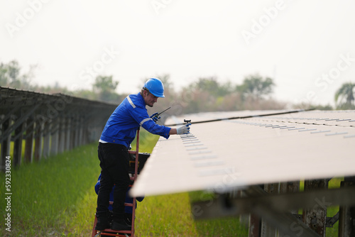 Electrician engineer with white helmet working at a photovoltaic farm, checking and maintenance equipment with instruments at industry solar power. photo