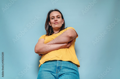Lower angle young woman crossed arms on blue studio background