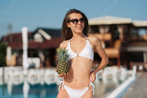 Girl relaxing and holding fruit by the hotel pool. Exotic summer diet. Tropical beach lifestyle © JJ Studio