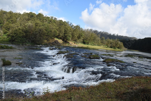 River flowing with green hills and blue sky