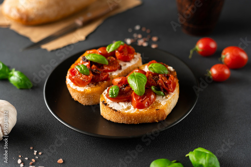 Bruschetta with Ricotto cheese and cherry Tomatoes, basil, garlic on a black background. Food. Food background
