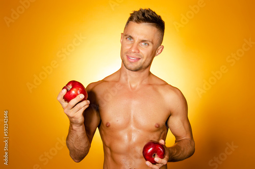 Young attractive Man with an athletic body on a diet. Orange background. Healthy food. 