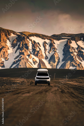 4x4 SUV car driving on dirt road and volcanic mountain background on Icelandic Highlands in summer at Landmannalaugar