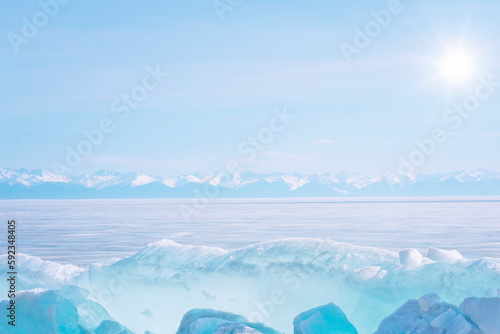 Winter landscape with ice hummocks sparkling in the sun and mountains of Baikal in Siberia at sunset.