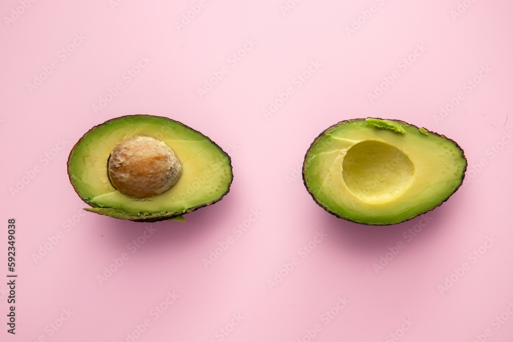 Top view of cut out avocado pieces on a pink surface