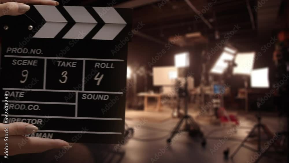 Human hands are using a clapperboard on set. Beginning of scene in film or TV television production. Concept of cinematography movie or video crew. Stage and filmmaking equipment background