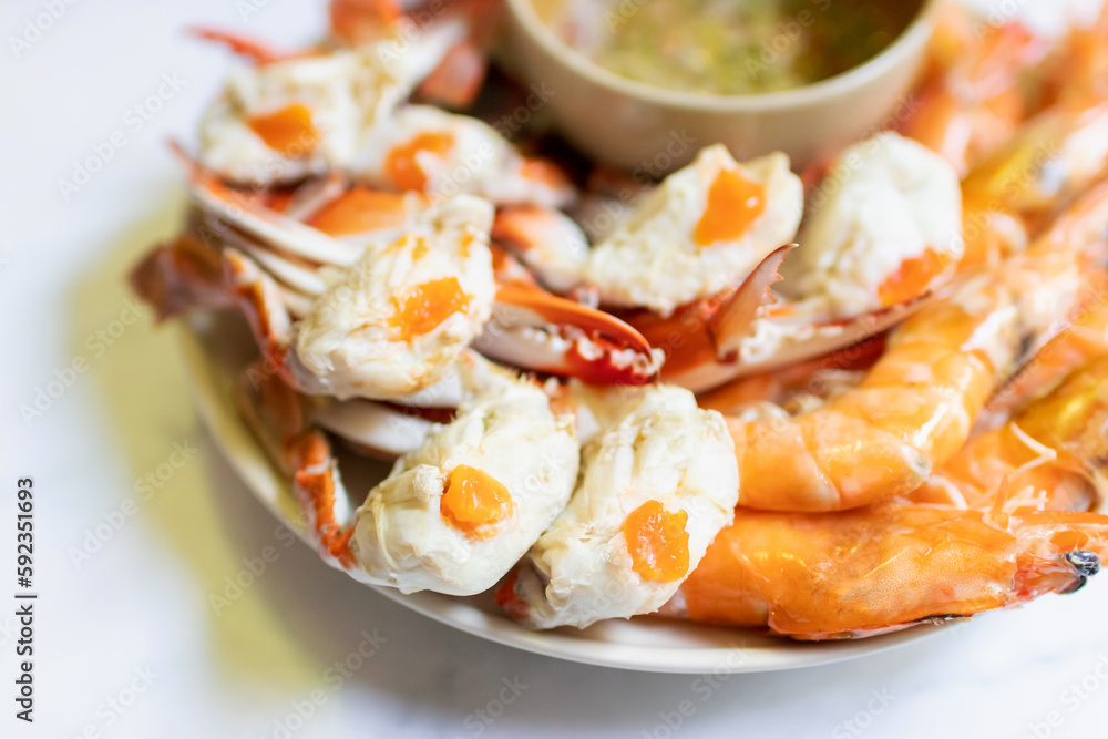 Steamed blue crab legs and shrimp on plate serving with spicy sauce. Steamed blue crab legs and shrimp on plate serving with spicy sauce.