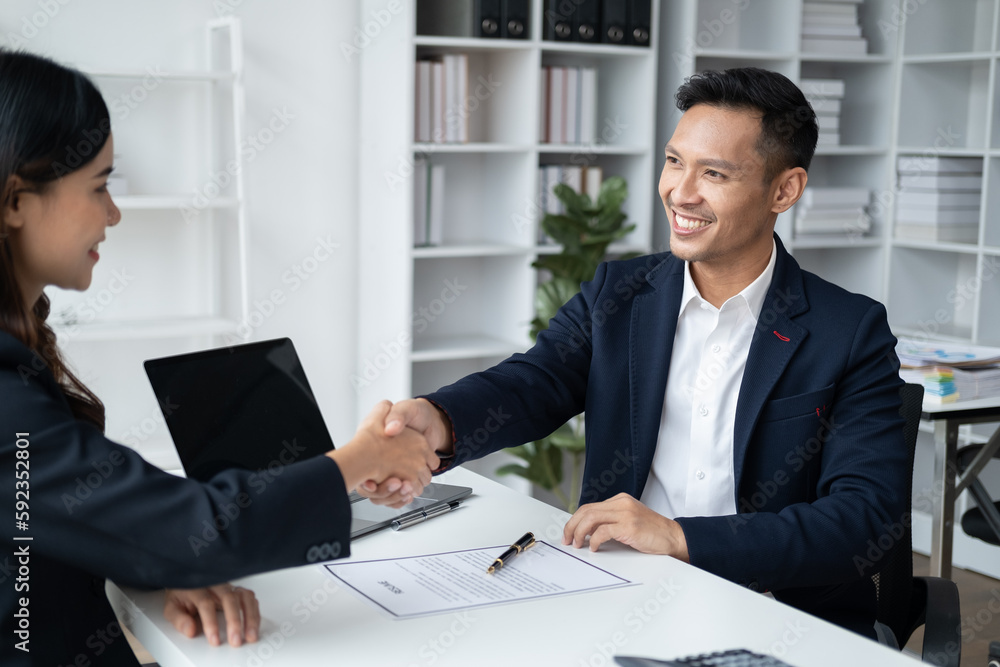Smiling manager shaking hands with an applicant after an interview.