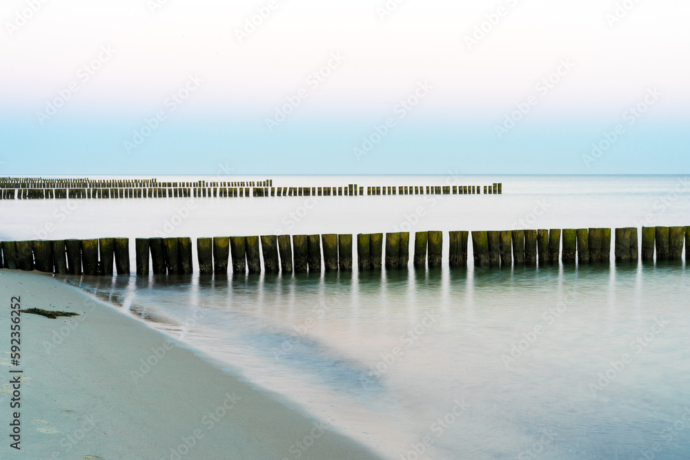 Groynes in the water of the Baltic Sea, blue water shines, the sun is shining, the perfect vacation day