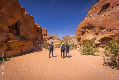 Petra w Jordanii. Trzech mężczyzn idących pustynią pomiędzy formacjami skalnymi. 